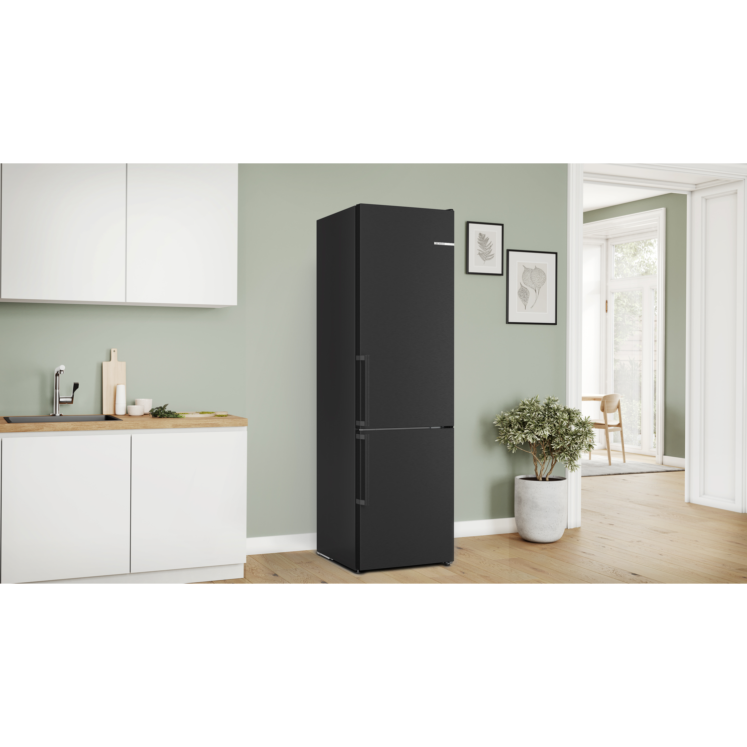 A black refrigerator with two doors, set in a kitchen with a light green wall.