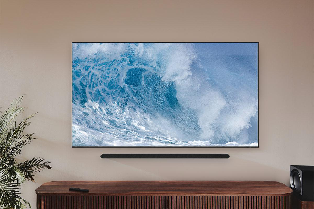 Ein moderner Fernseher, der ein Wellenbild anzeigt, an einer Wand über einer Soundbar und einem Schrank montiert.