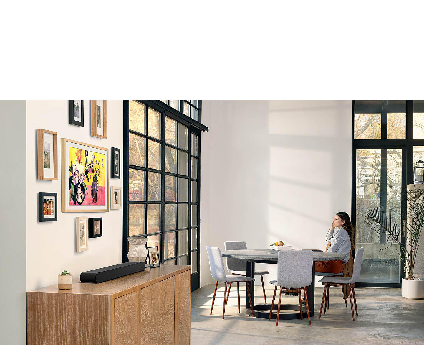 Frau in einem Raum, die eine Wand mit Kunst und Soundbar betrachtet.