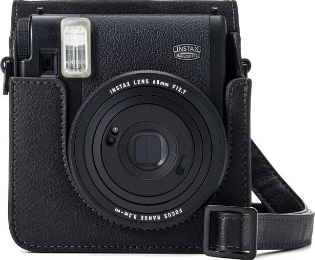 Fotocamera Instax nera in una custodia in pelle. Cinturino nero attaccato. Obiettivo visibile.