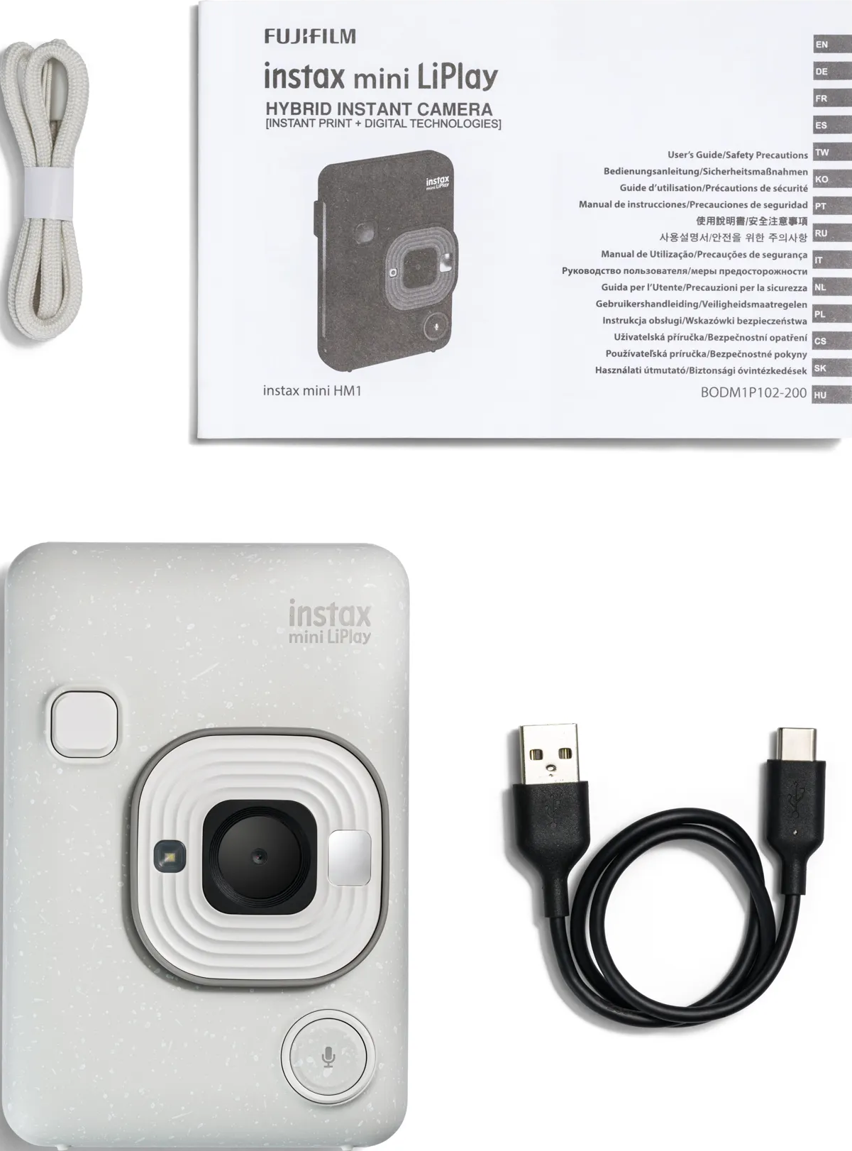 Weiße Instax Kamera, Zubehör und Anleitung auf weißem Hintergrund.