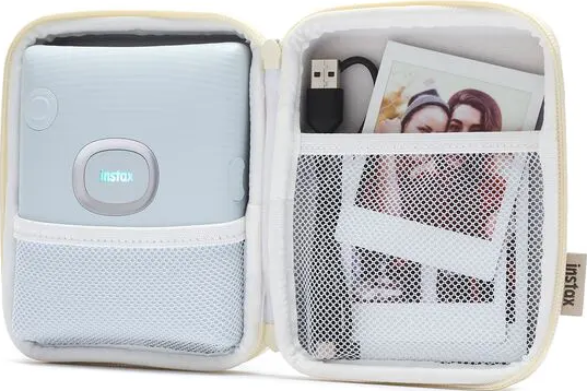Geöffnete weiße Instax-Kameratasche mit Fotos und Zubehör.