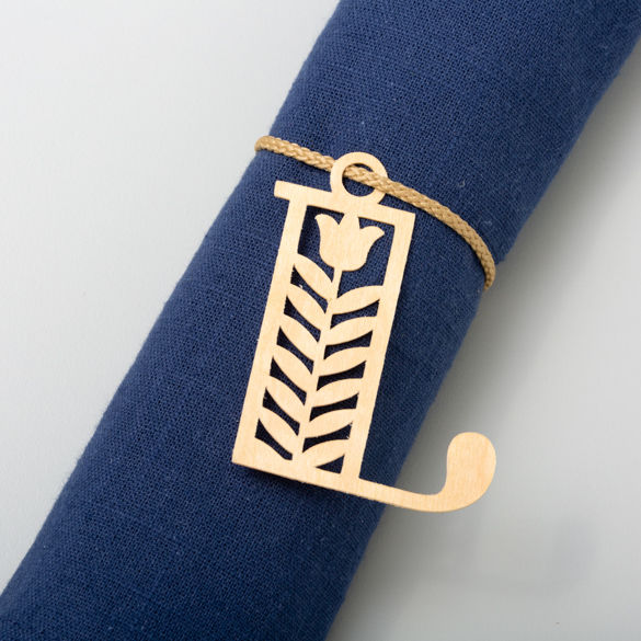 Serviettenring aus Holz mit ausgeschnittenem Buchstaben 'L' und floralem Design. Blaue Serviette.