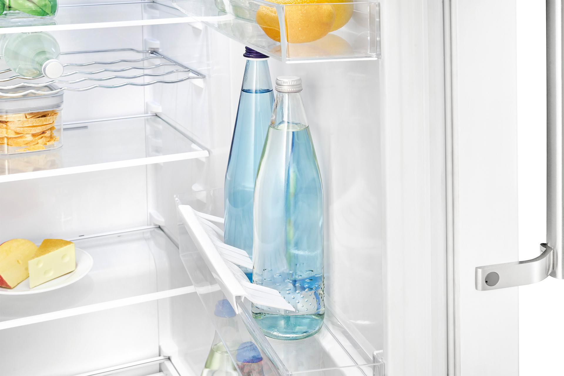 Kühlschrankinnenraum mit Wasserflaschen, klaren Regalen und verschiedenen Lebensmitteln.