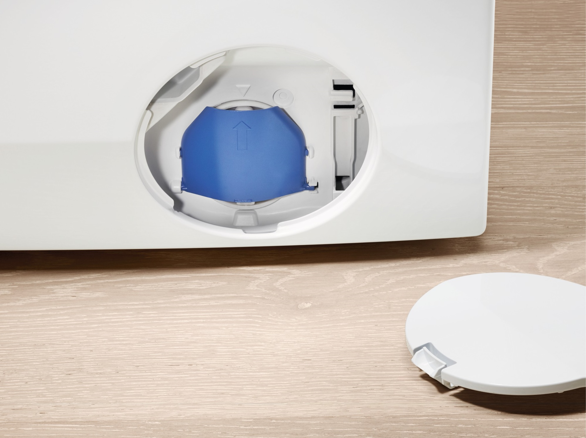 Biały plastikowy element z niebieskim elementem w środku i odłączoną pokrywą na drewnianej powierzchni. Zbliżenie.