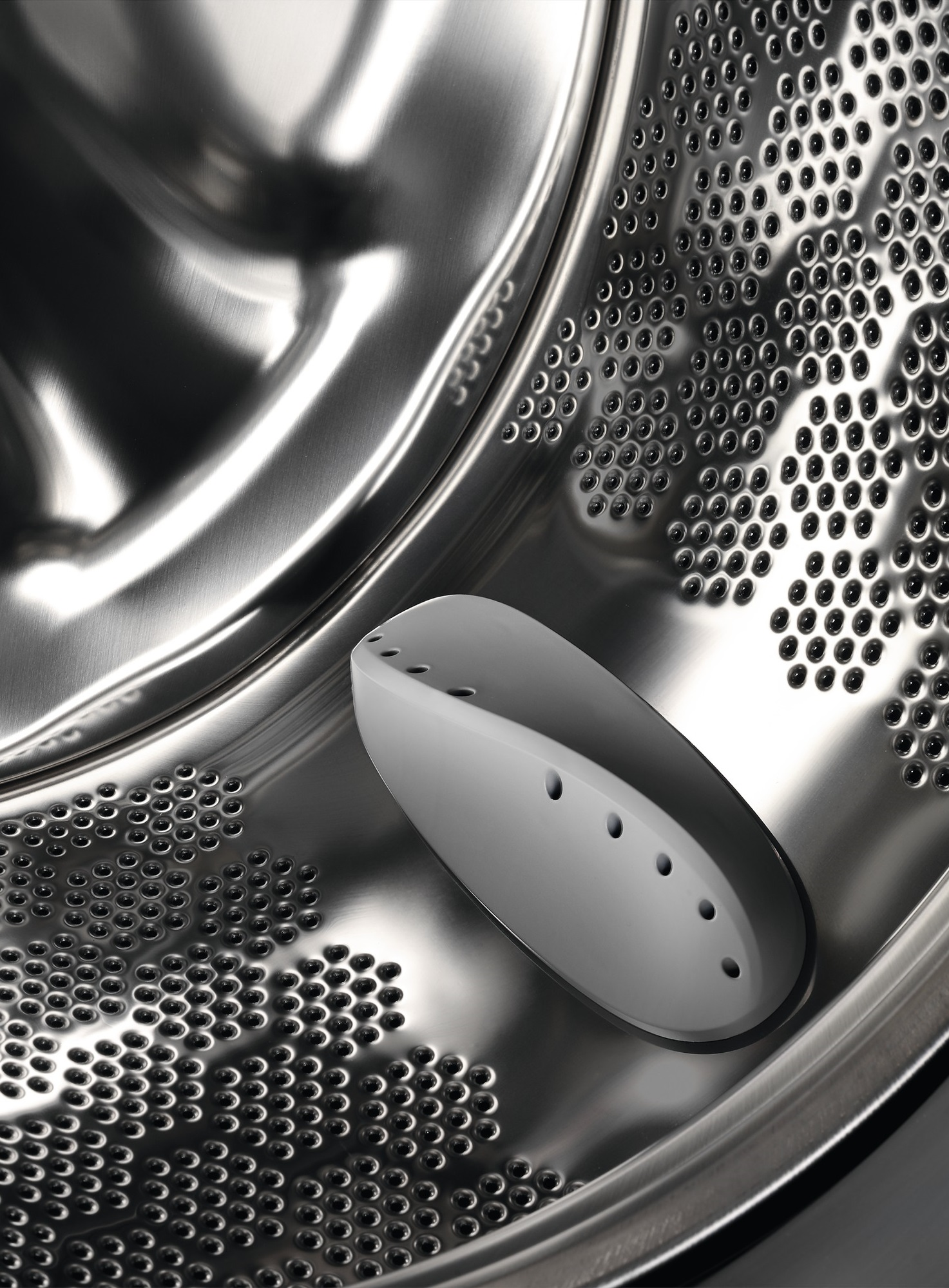 Wnętrze bębna pralki z białym plastikowym elementem.