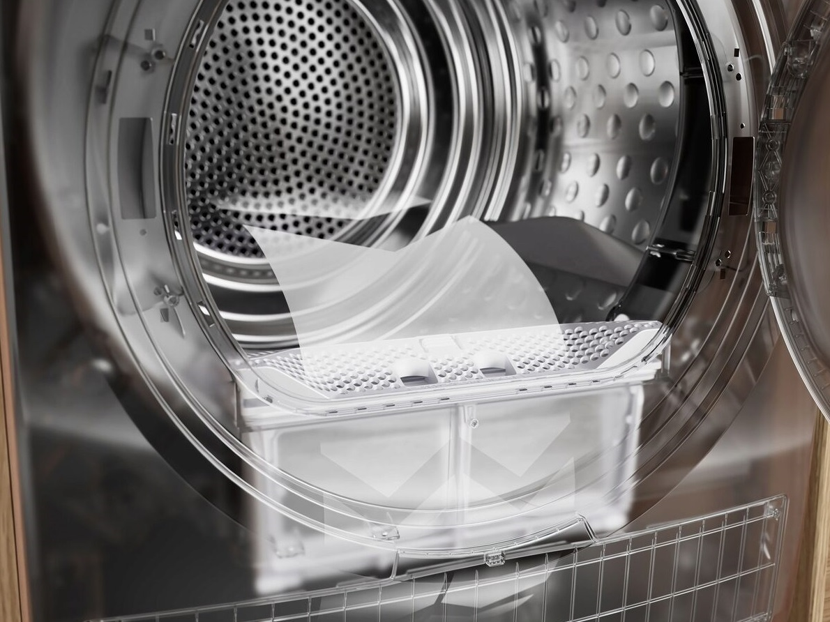 Zbliżenie bębna suszarki z filtrem na miejscu. Tło ukazuje wnętrze i drzwi suszarki.