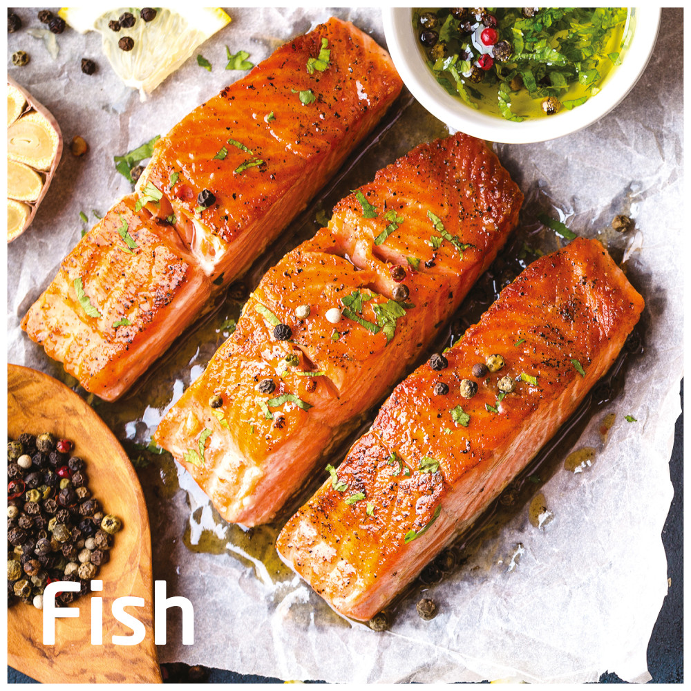 Three grilled salmon fillets with herbs and spices, with a small bowl of sauce.