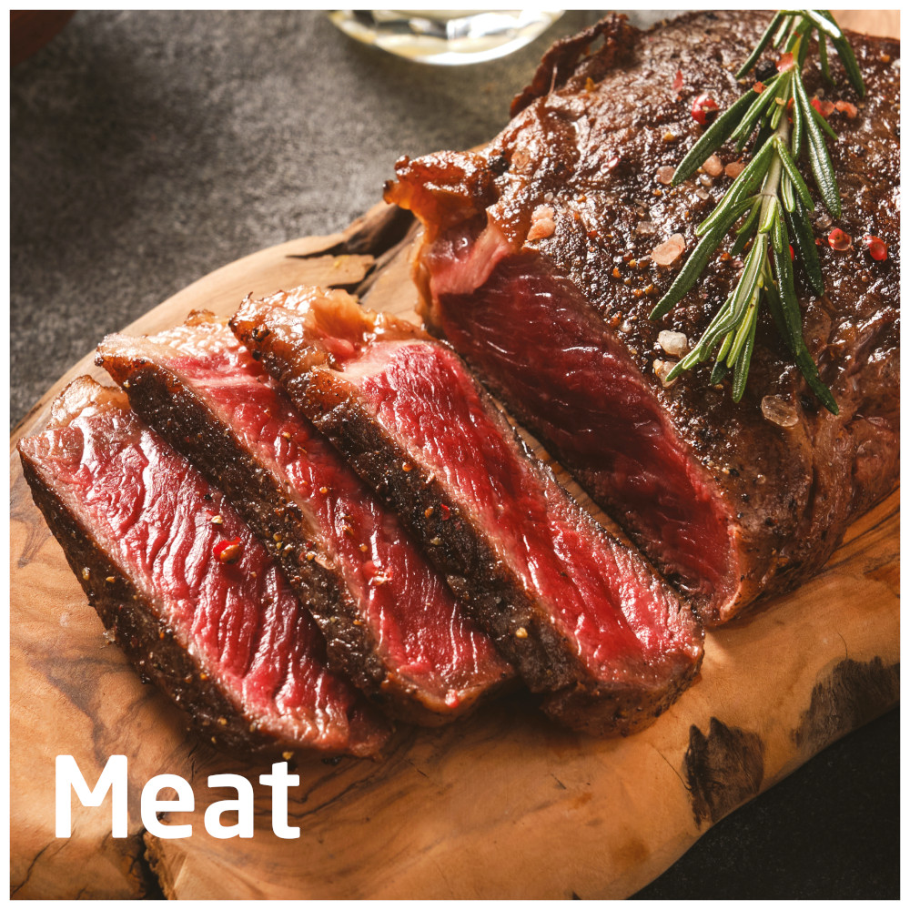 Sliced steak on a wooden board. Red meat with herbs and seasoning. The word Meat is written.