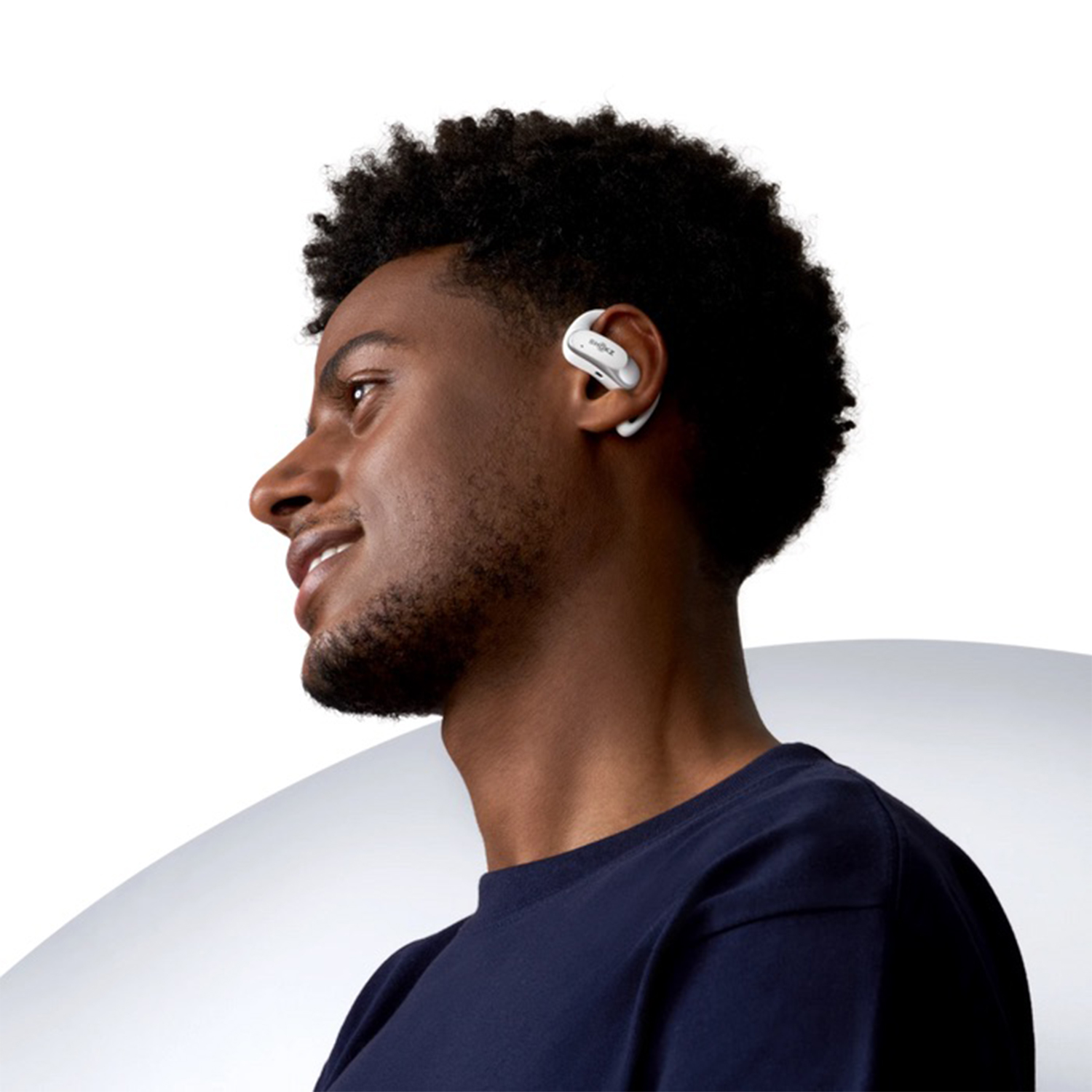 Un uomo con la pelle scura indossa un auricolare bianco.