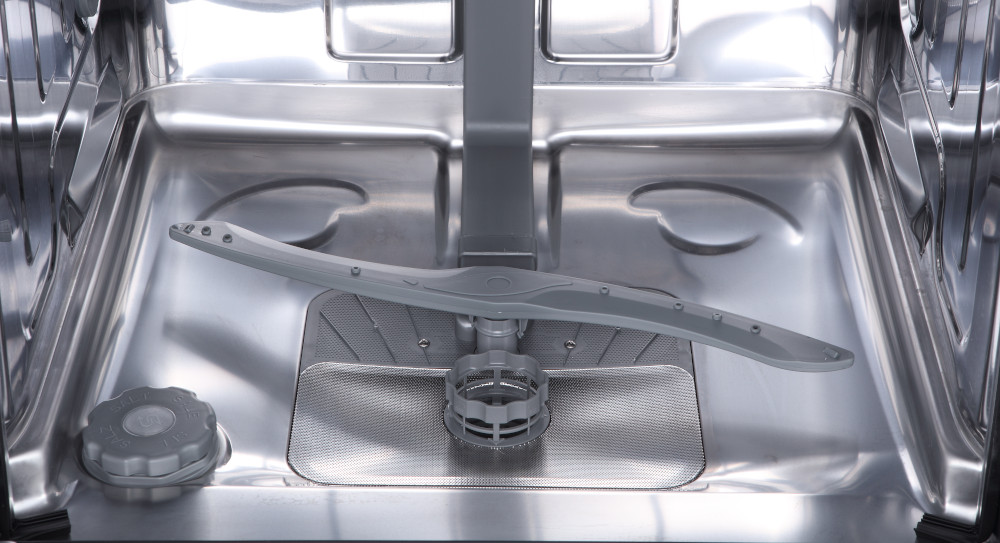 Inside of a stainless steel dishwasher with a spray arm and a filter at the bottom.