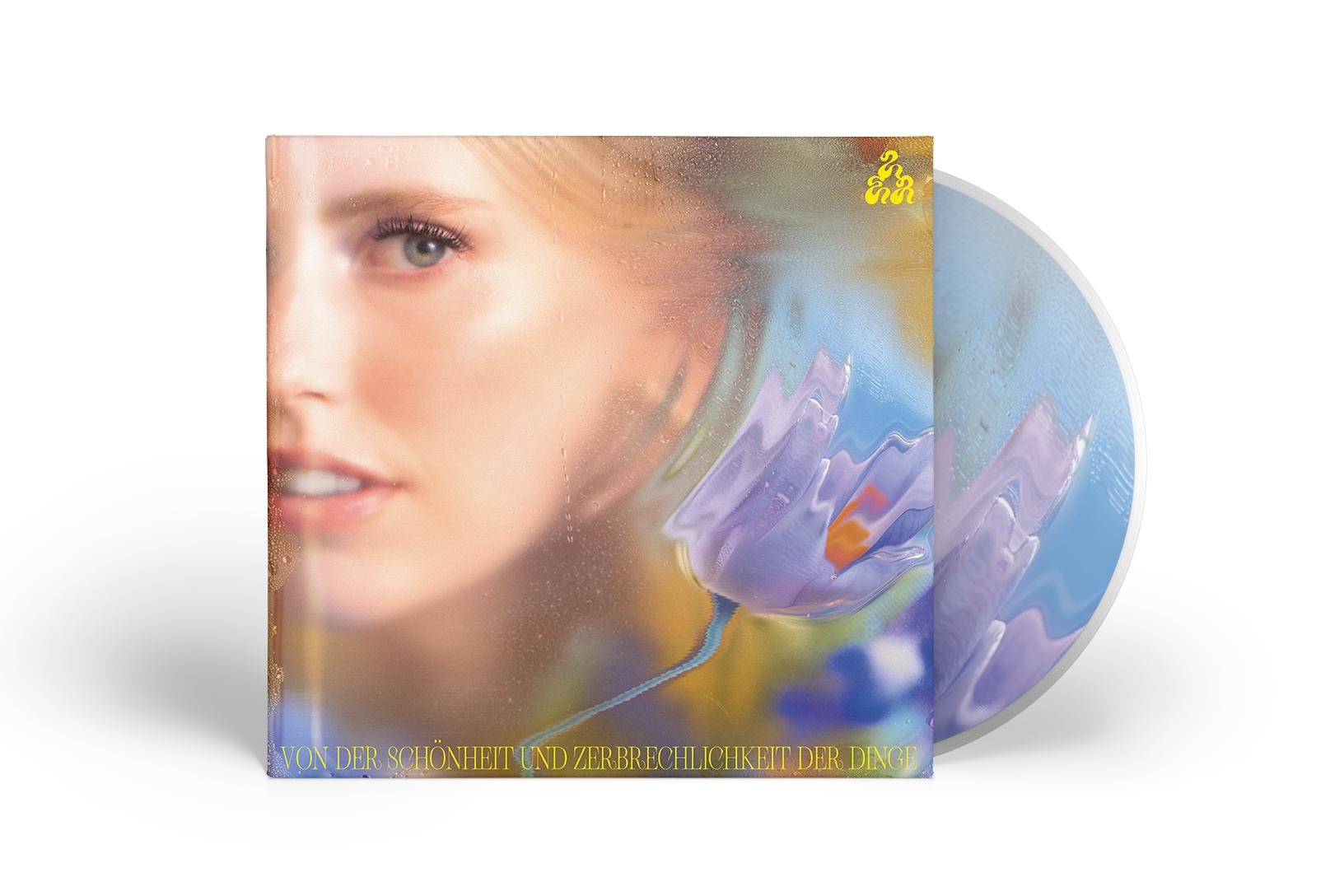 Albumcover mit Frauen-Gesicht und CD. Text auf Deutsch. Blau, Gelb und Wasserfarben.