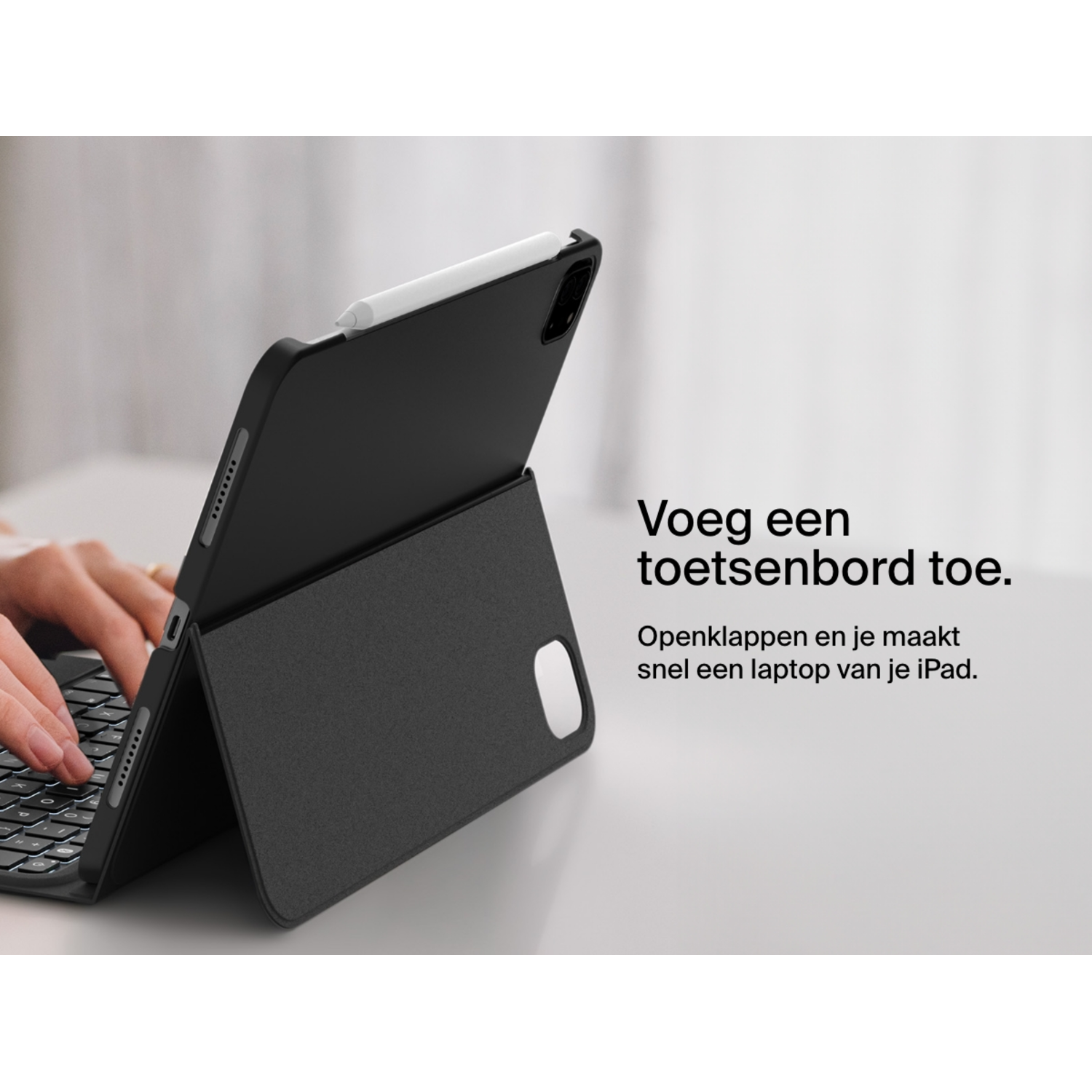 Black iPad on a keyboard case with a white pencil, hands are typing.