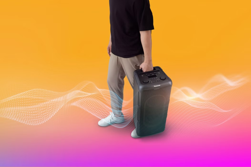 Egy személy egy fekete Panasonic hangszórót visz színes háttérrel.
