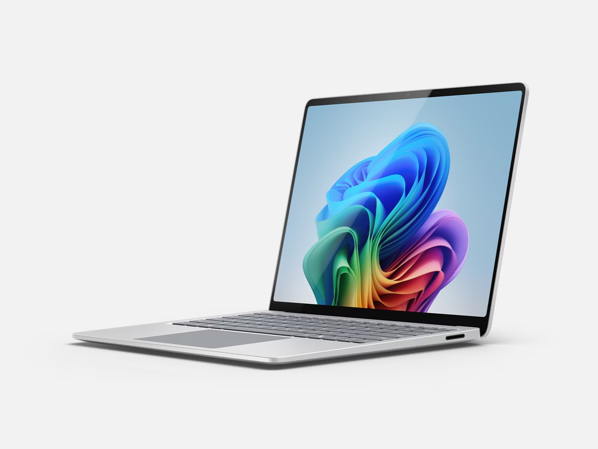 Zilveren laptop open op een witte ondergrond, met een kleurrijke abstracte achtergrond.