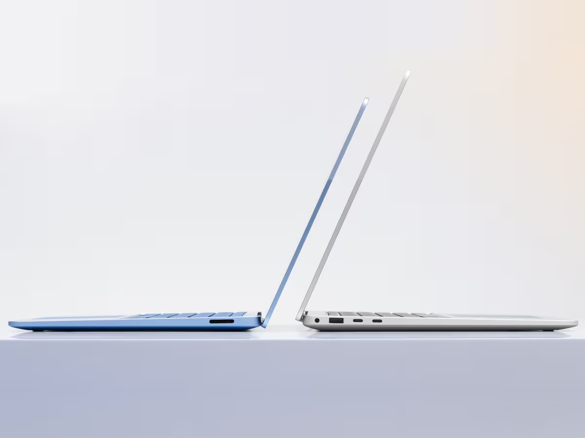 Twee laptops, één blauw en één zilver, naast elkaar op een wit oppervlak.