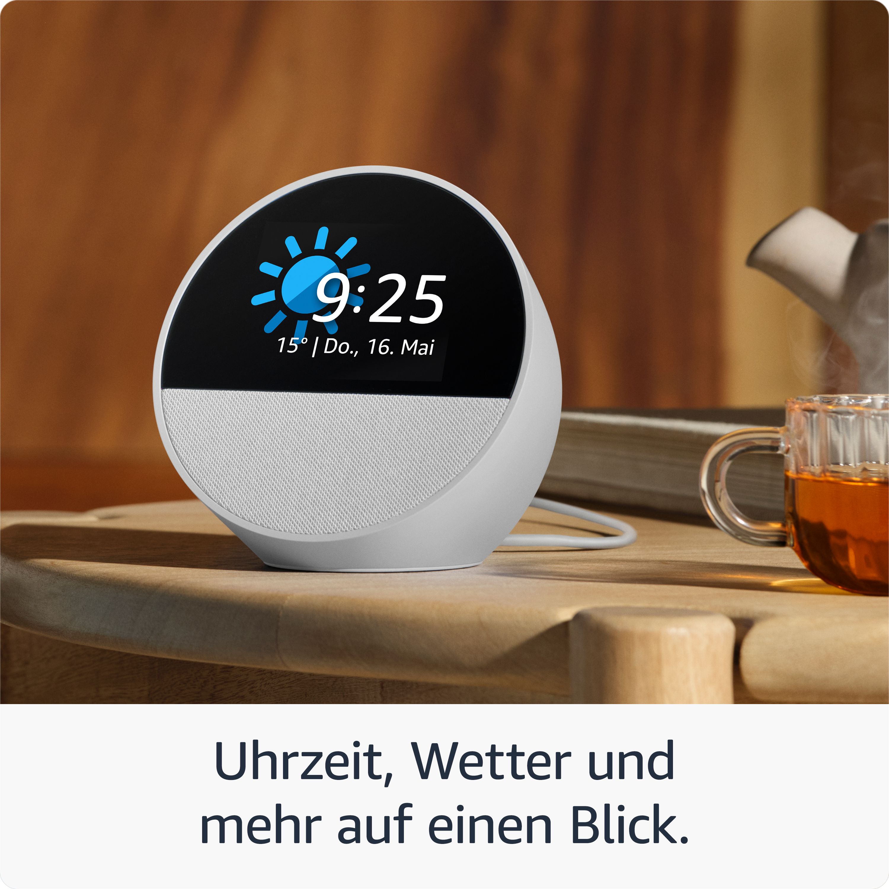 Smarter Lautsprecher mit Uhrzeit- und Wetteranzeige, Tee daneben.