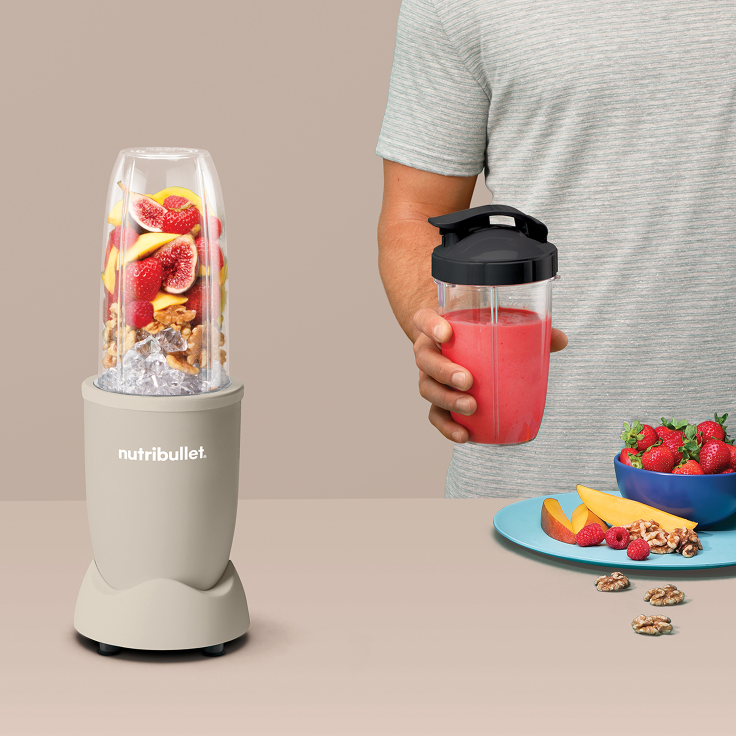 NutriBullet turmixgép gyümölccsel és dióval, személy smoothie-t tart.
