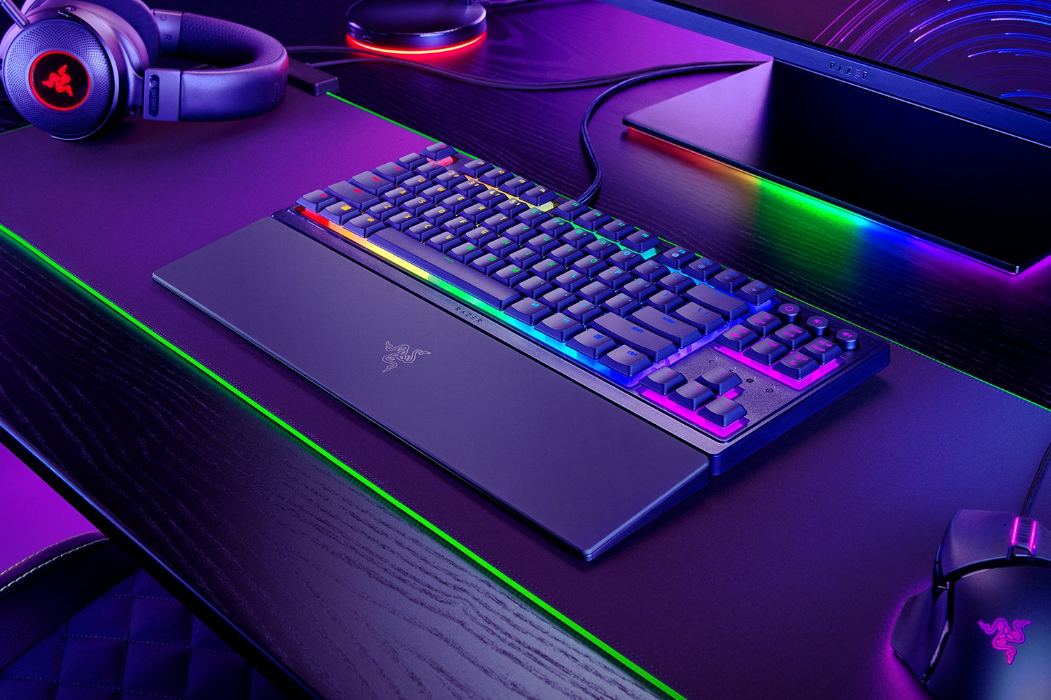 Configurazione di gioco con tastiera retroilluminata su una scrivania. Altri accessori includono cuffie e mouse.
