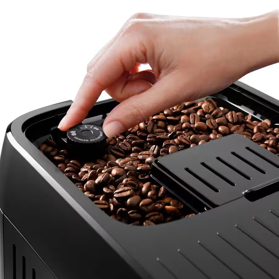 Una mano che regola il quadrante di regolazione della macinatura di una macchina da caffè nera, chicchi di caffè in vista.
