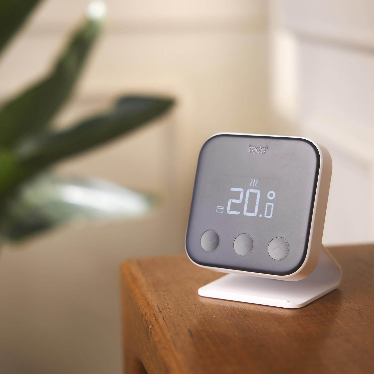 Black smart thermostat with a screen displaying 20.8 on a wooden surface.