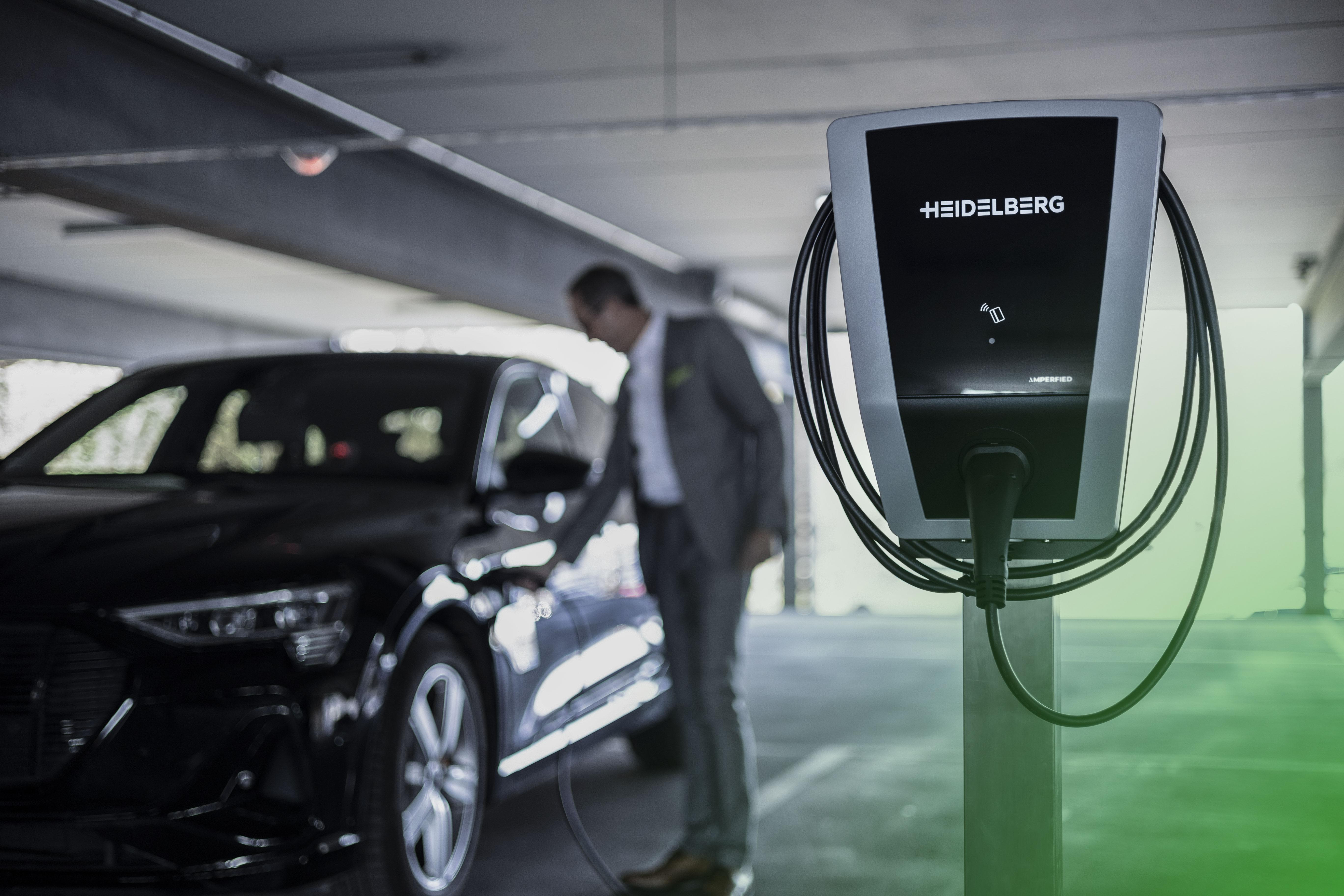 Eine Person in der Nähe einer Ladestation, die ein Elektroauto auflädt.