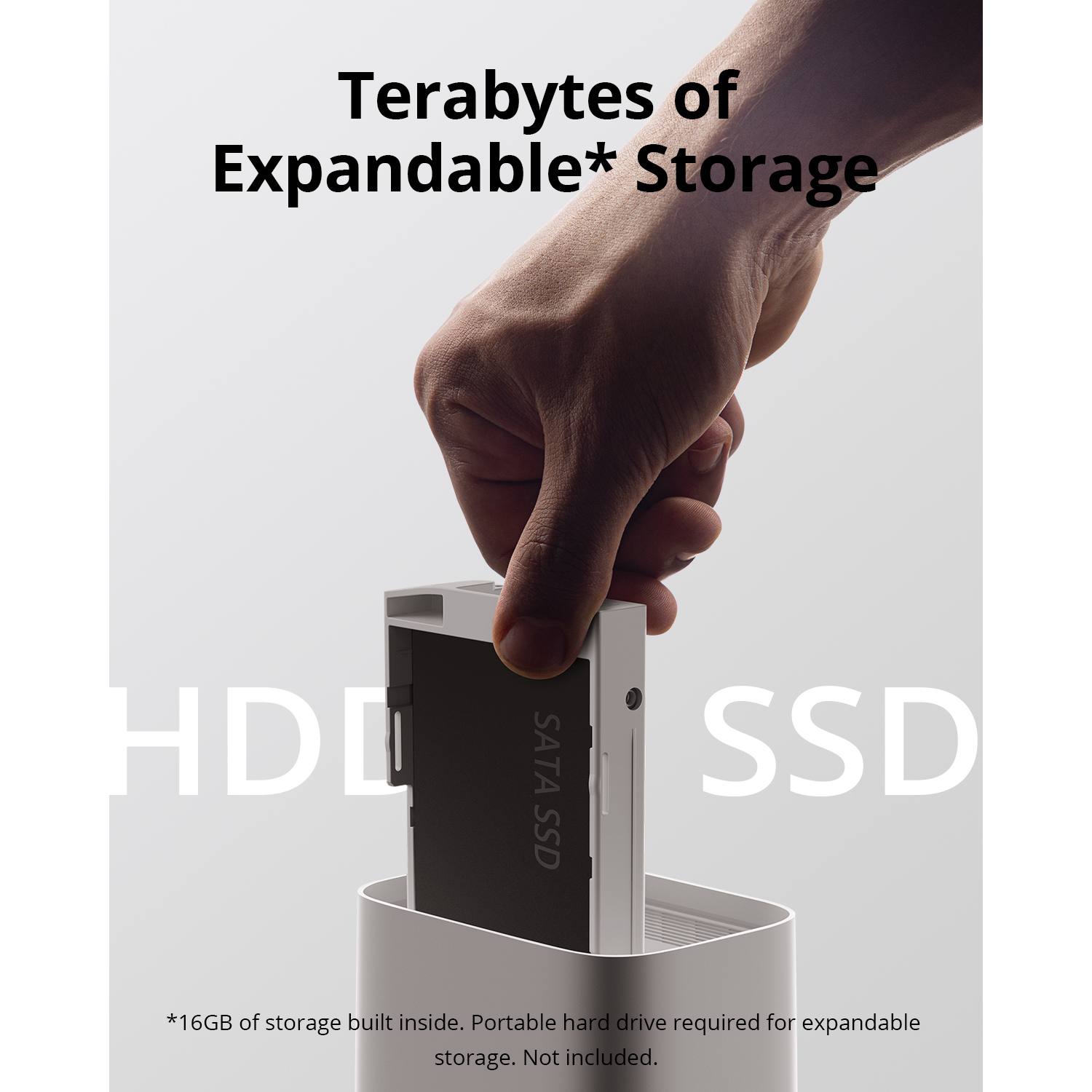 A hand inserts an SSD into a white storage device. Text on the SSD.