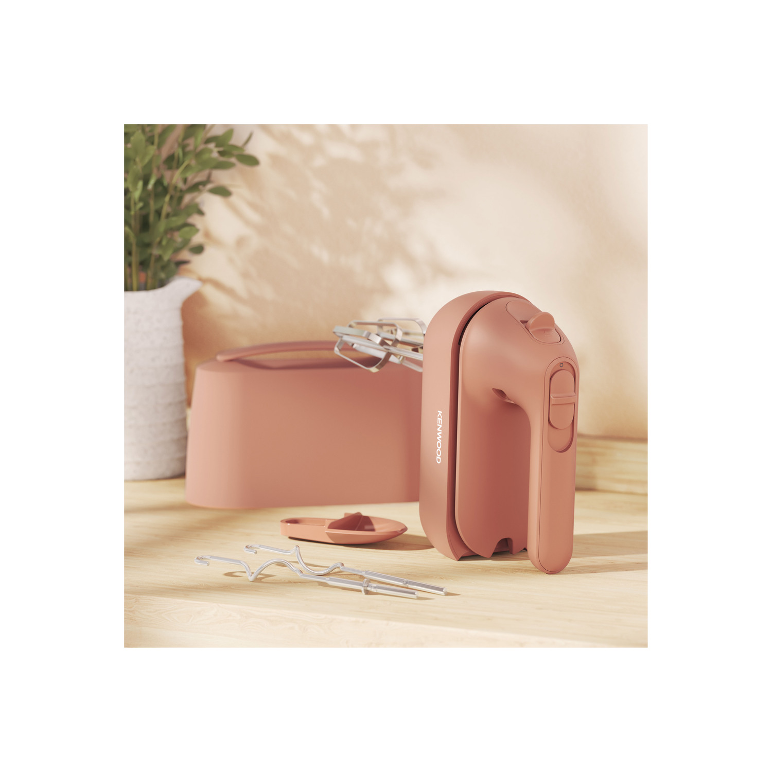 Pink electric hand mixer with accessories.