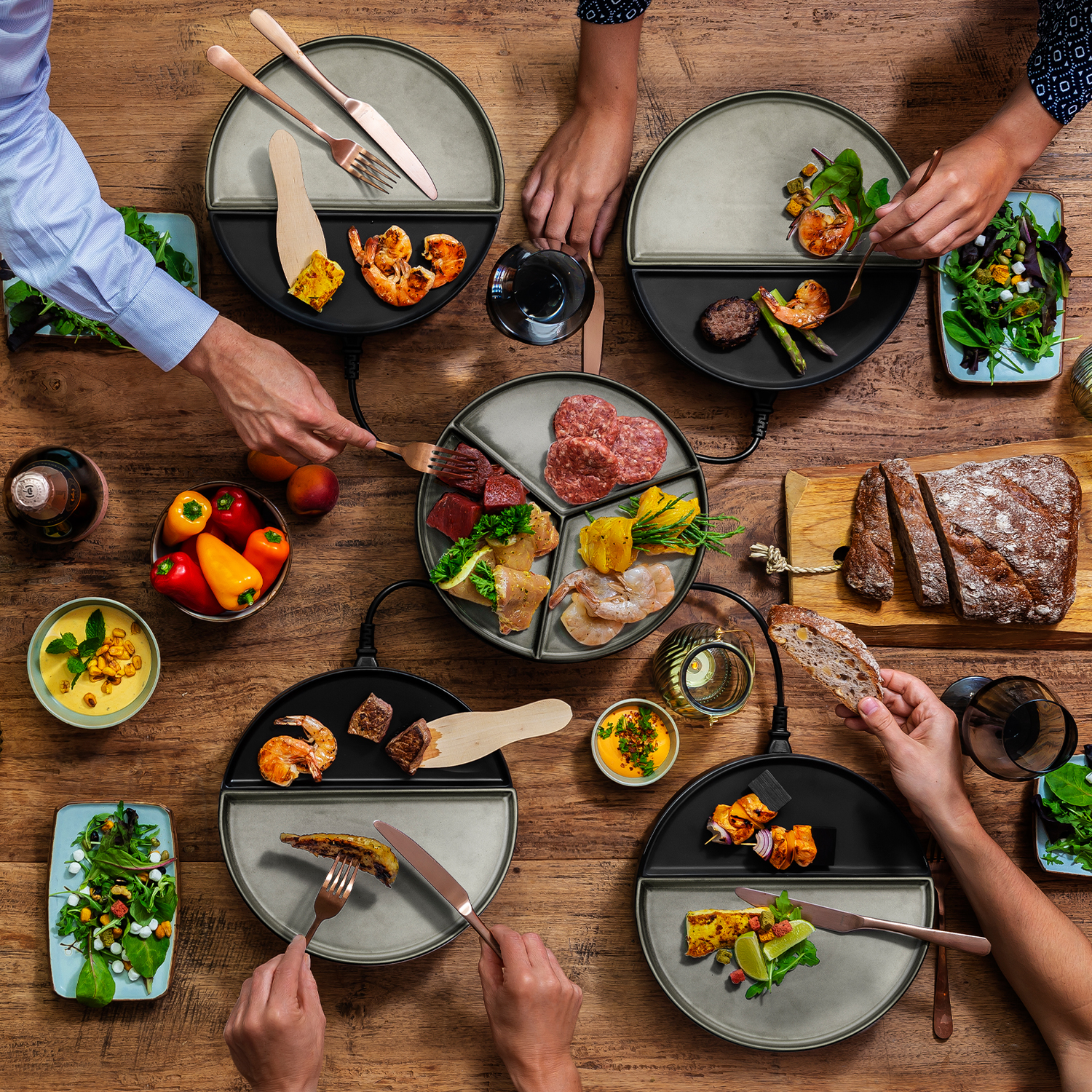A table setting with multiple people eating food from divided plates. 