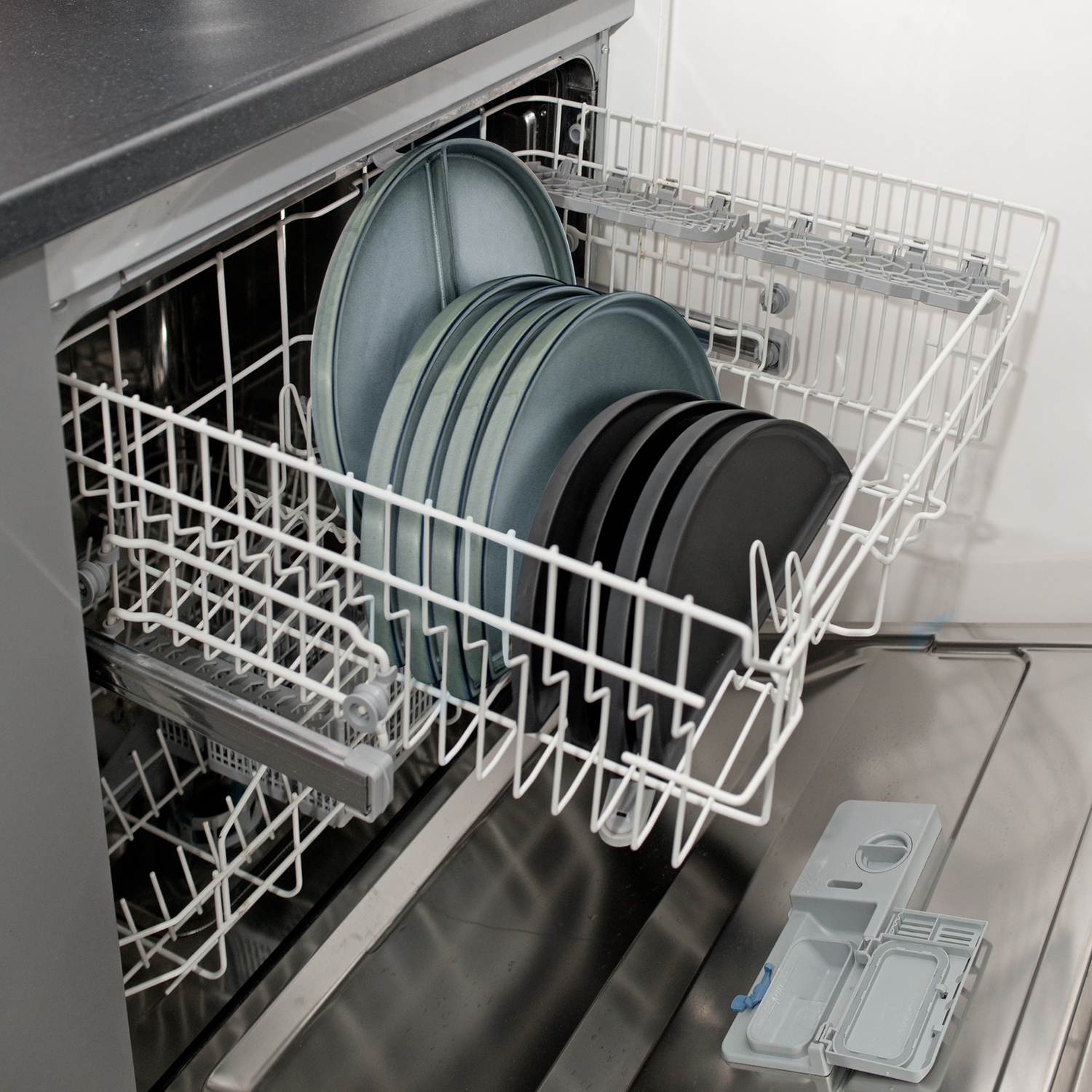 Dishwasher loaded with plates and a detergent compartment.