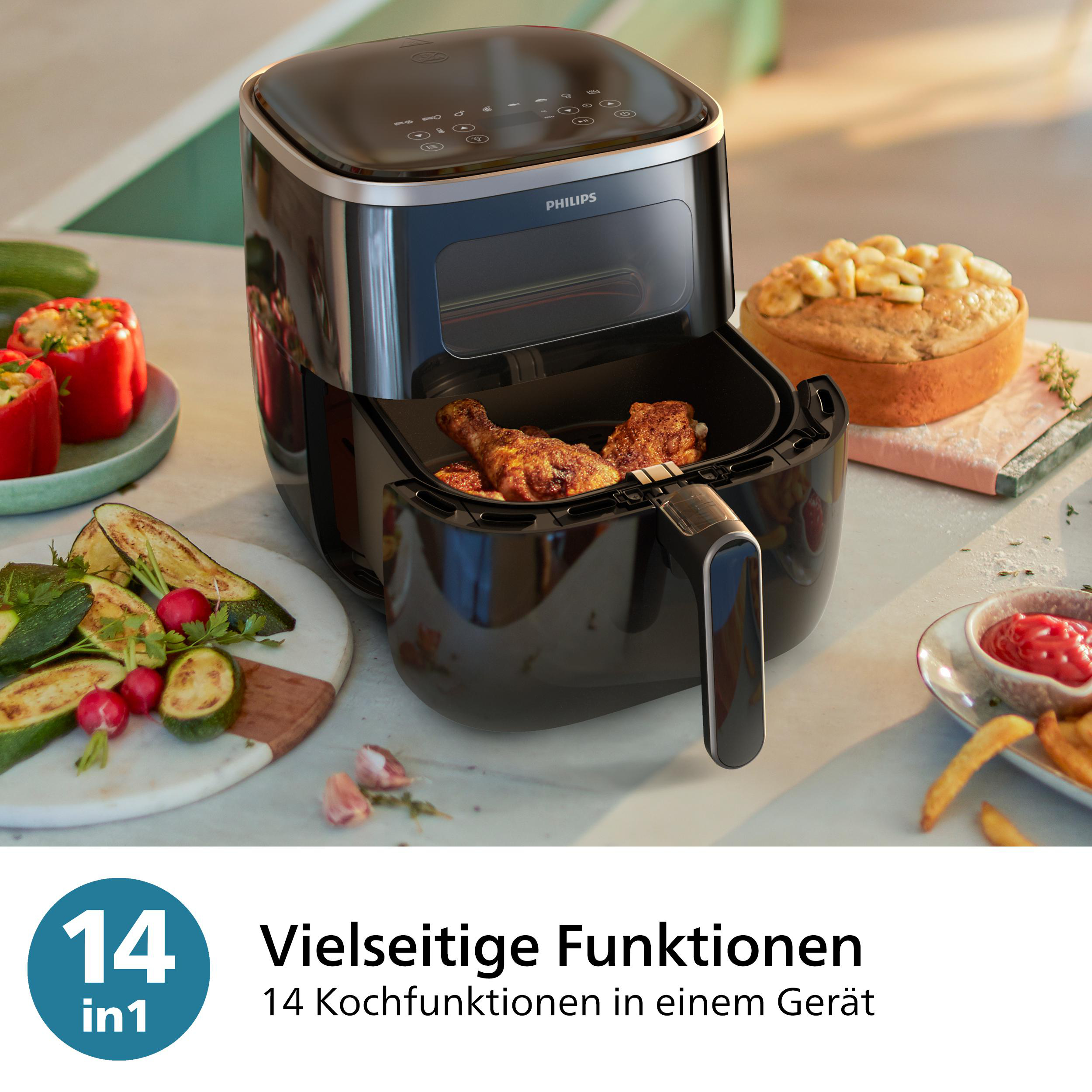 Schwarze Heißluftfritteuse mit Hähnchen darin. Es gibt Gemüse und Saucen drumherum.
