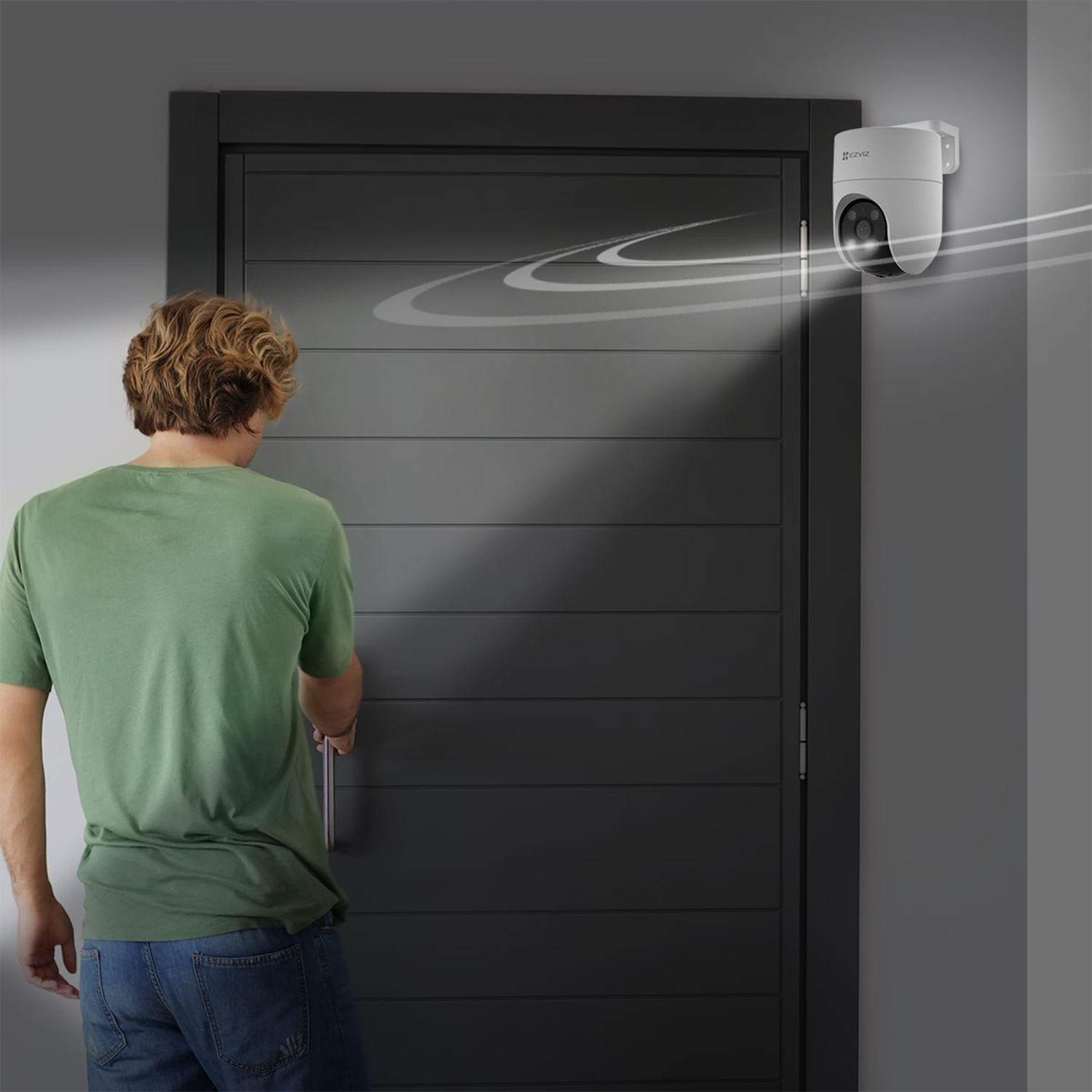 Uomo vicino a una porta e una telecamera di sicurezza bianca. La telecamera è attivata.