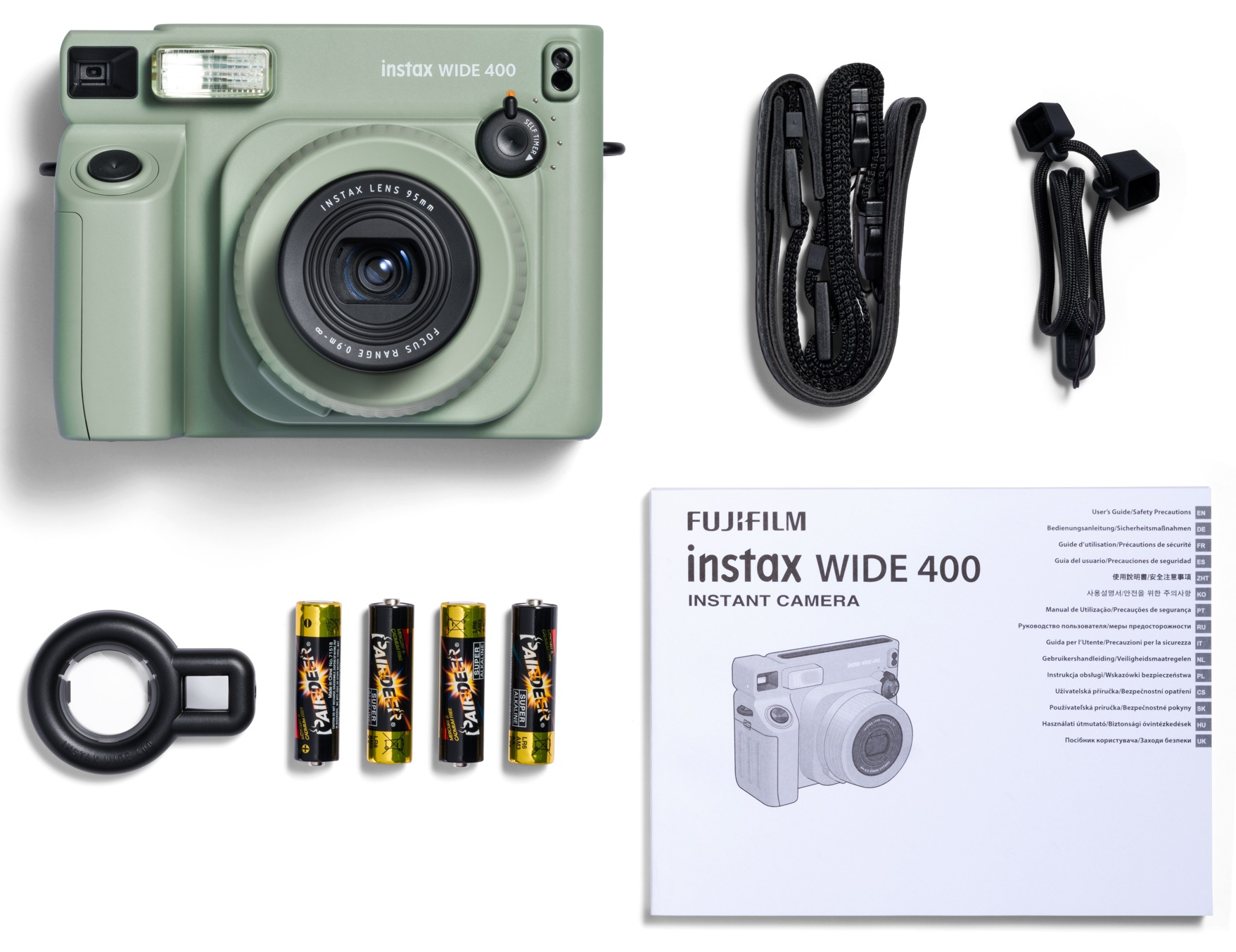 Zielony aparat z akcesoriami, w tym bateriami i paskiem, na białym tle.