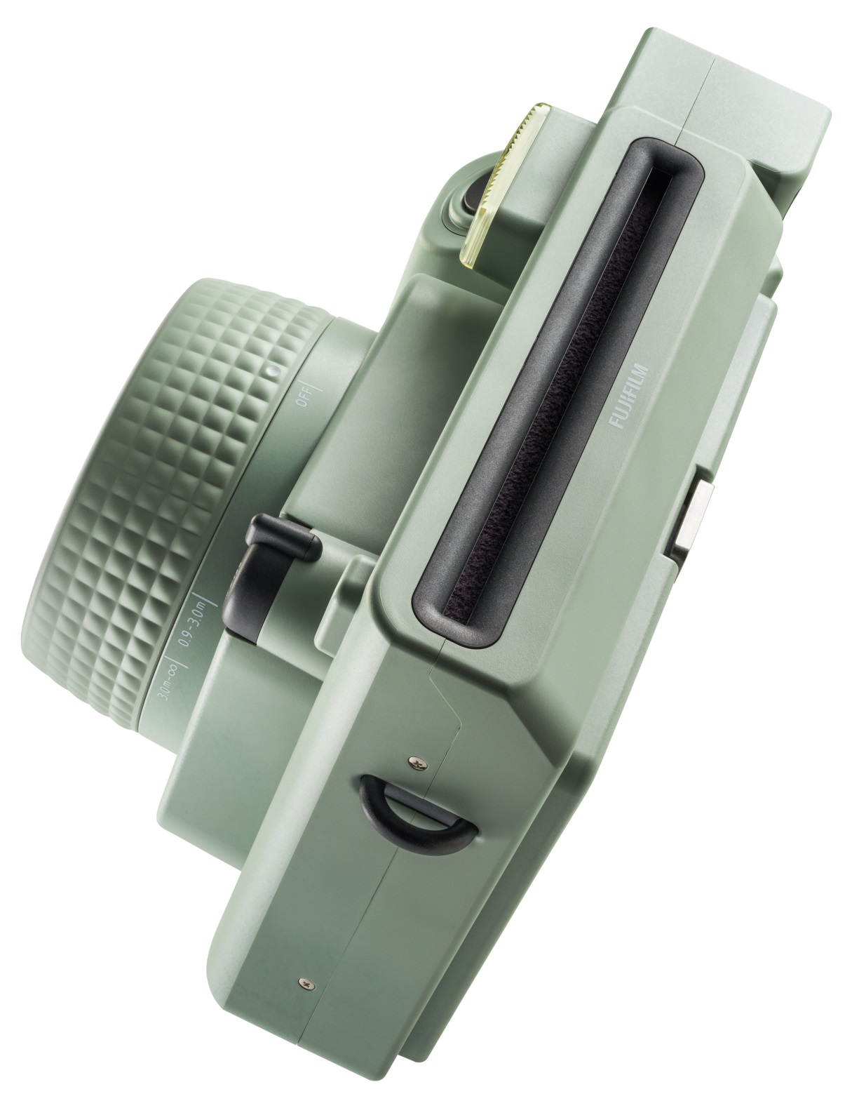 Zielony aparat Instax, pod kątem, z widocznym obiektywem, lampą błyskową i gniazdem na film.