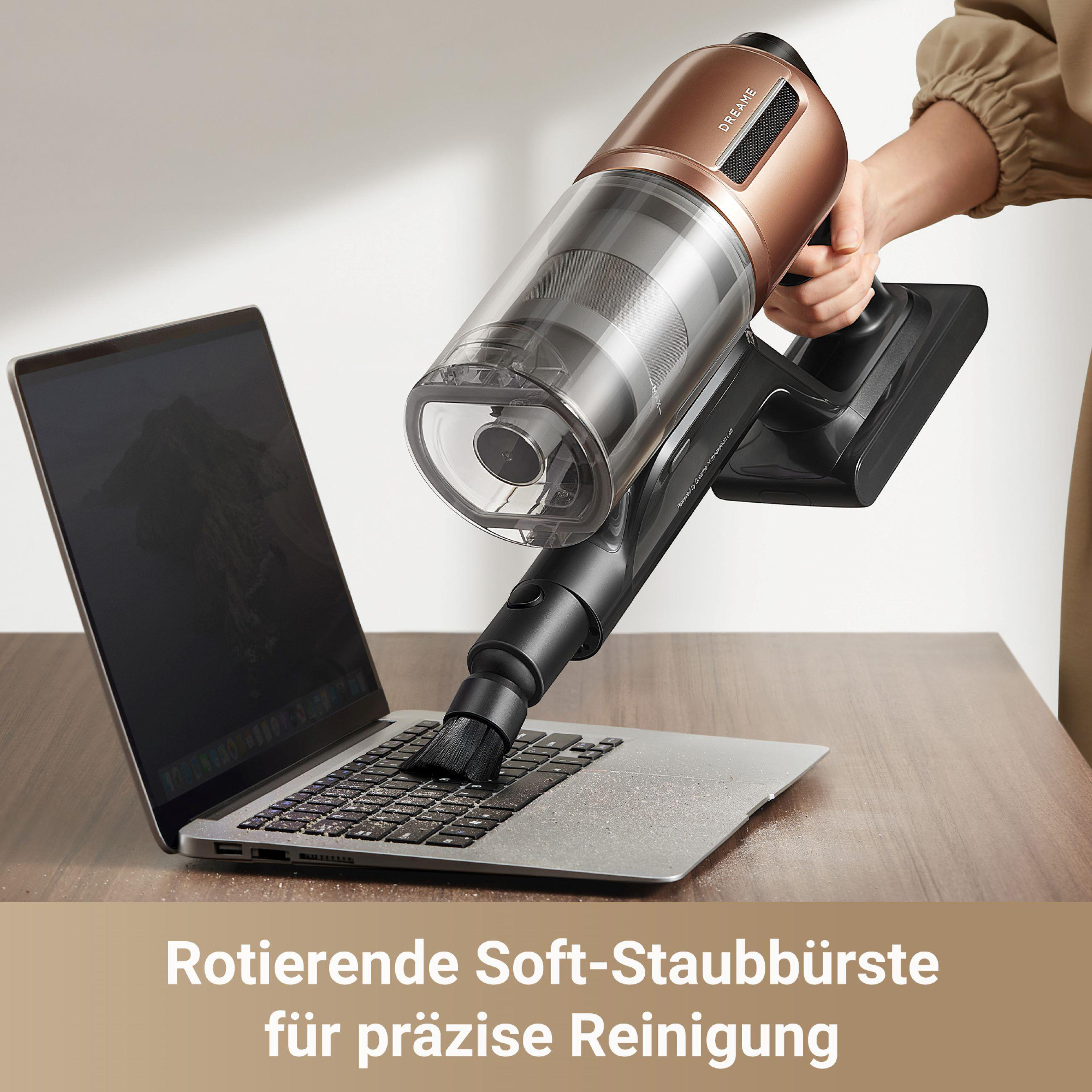 Eine Person reinigt eine Laptop-Tastatur mit einem Staubsauger-Bürstenaufsatz.