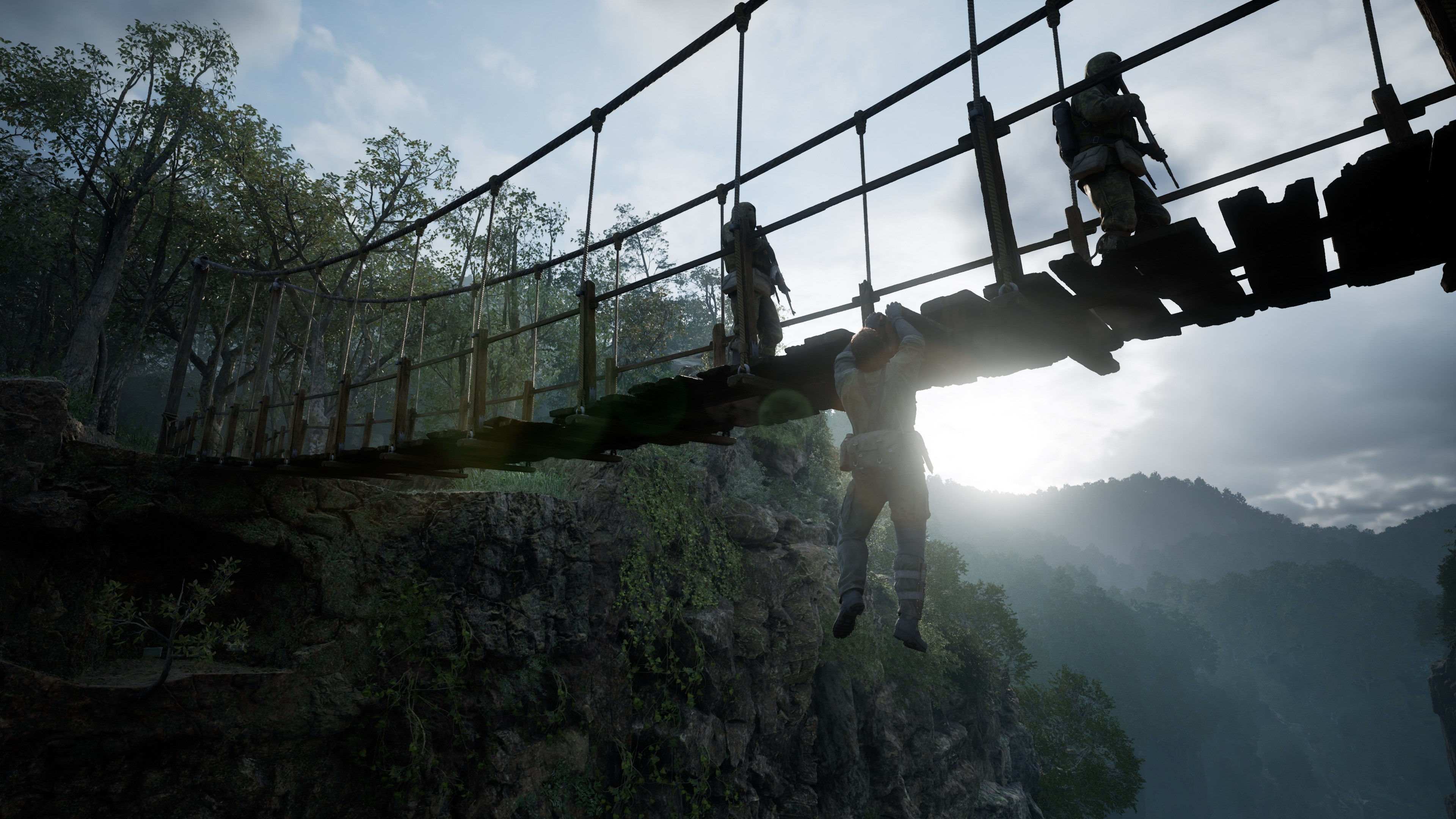 Des soldats traversent un pont de bois dans une forêt. L'un est suspendu au pont. Montagnes et ciel en arrière-plan.
