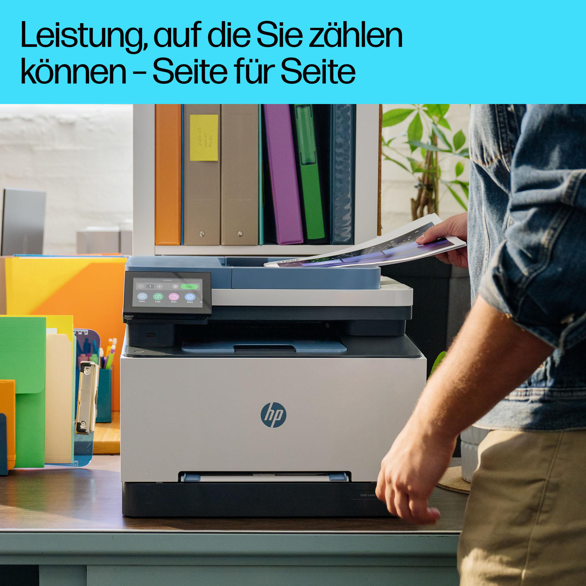 Ein Schreibtisch mit einem HP-Drucker, eine Person hält Papiere, Büromaterial im Hintergrund.