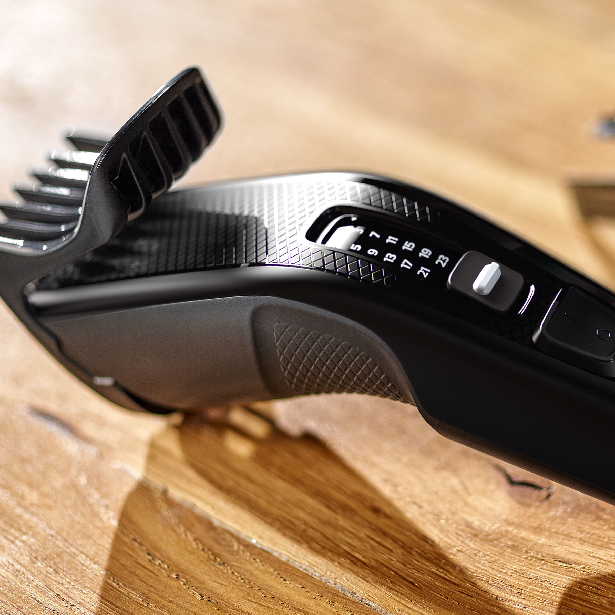 Czarna maszynka do strzyżenia włosów, pokazująca ostrze i ustawienia długości cięcia.