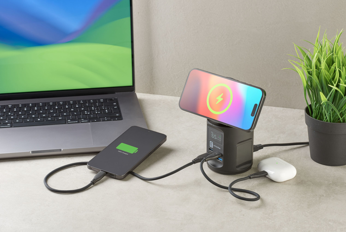 Estación de carga con dos teléfonos, una laptop y auriculares. Una laptop a la izquierda, la estación en el centro.