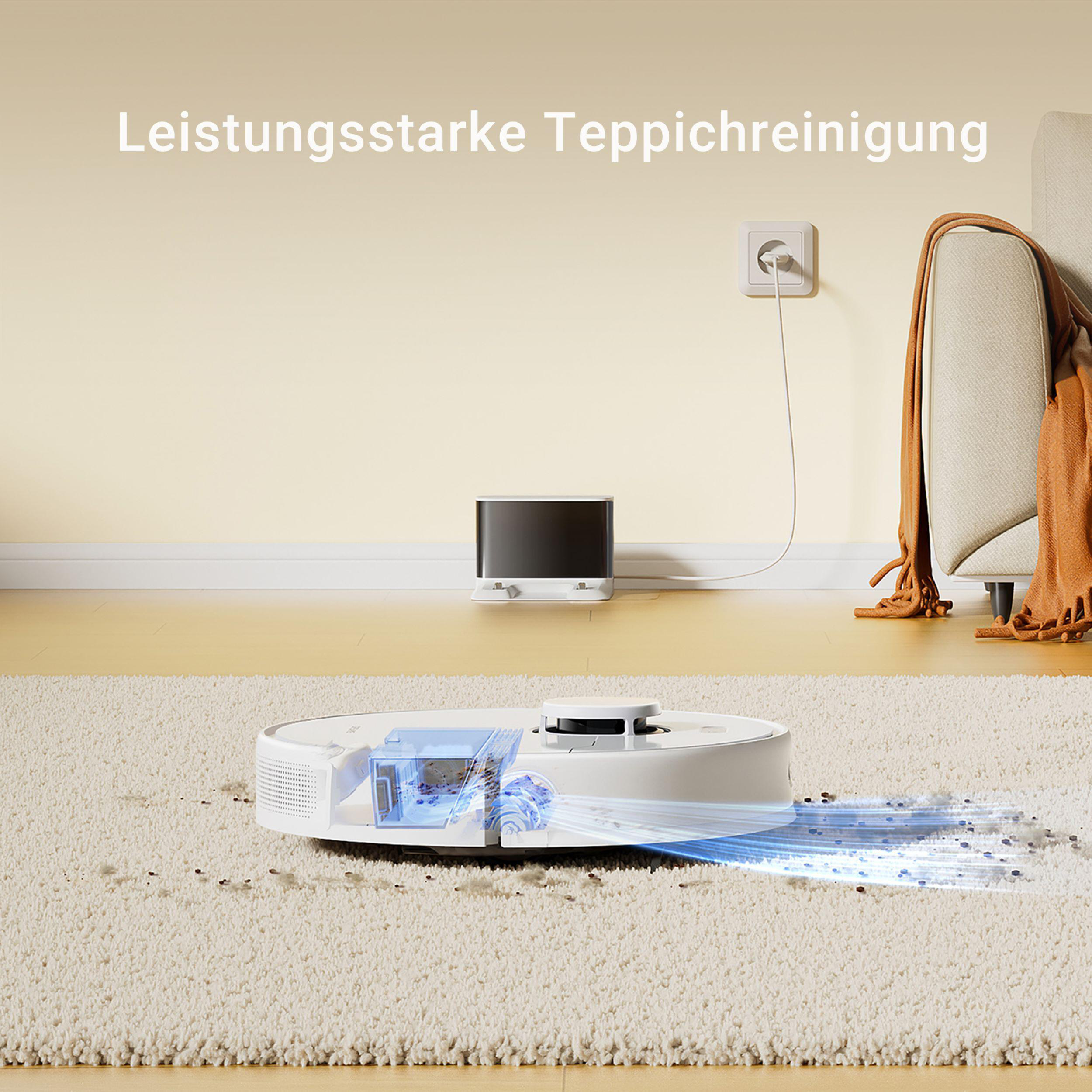 Weißer Roboter-Staubsauger reinigt weißen Teppich. Hintergrund ist eine beige Wand, Sofa und Ladestation.