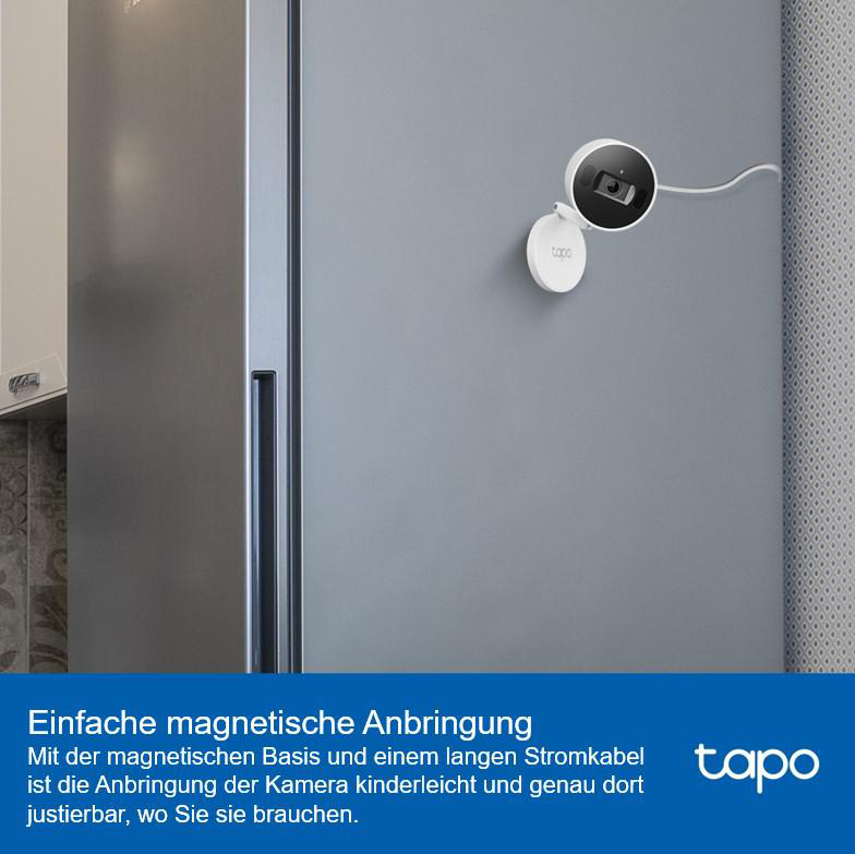 Eine weiße Kamera mit Magnetfuß, die an einer grauen Kühlschranktür befestigt ist, mit Text.