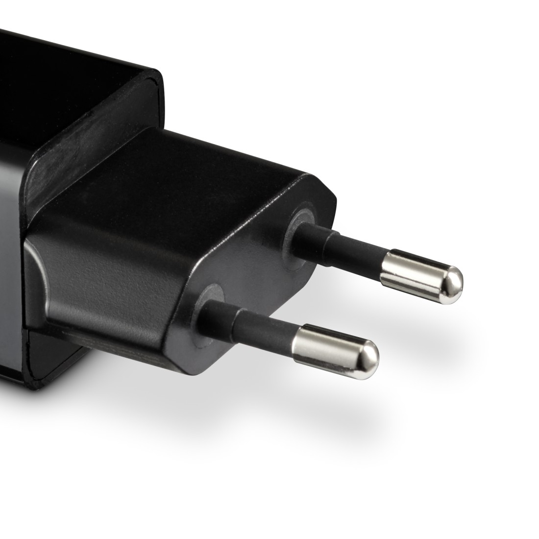 Schwarzer Netzadapter mit zwei Stiften. Weißer Hintergrund.