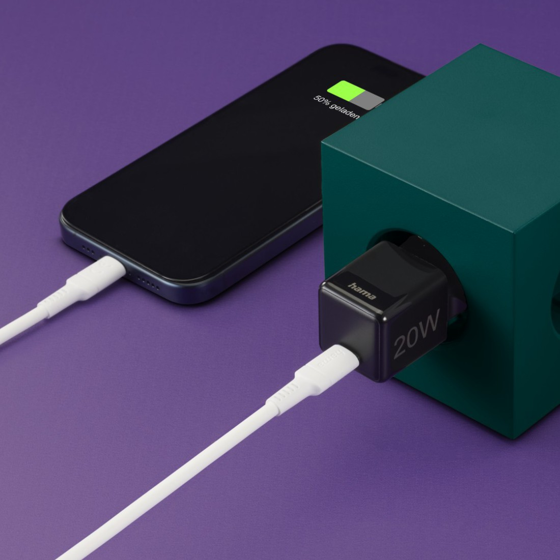 Telefon lädt mit weißem Kabel von einem schwarzen 20W-Ladegerät in einem grünen Würfel. Lila Hintergrund.