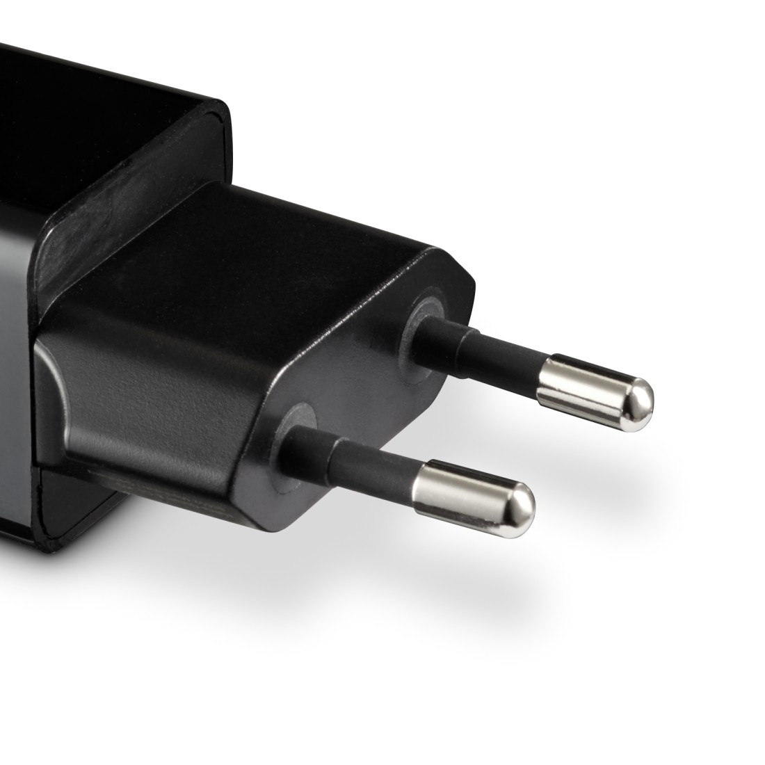 Ein schwarzer Netzstecker mit zwei silbernen Stiften, auf einer weißen Oberfläche.