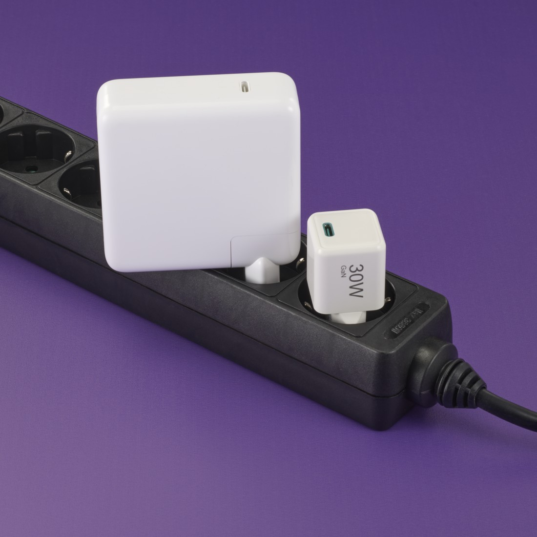 Weiße und schwarze Netzadapter an einer Steckerleiste angeschlossen.