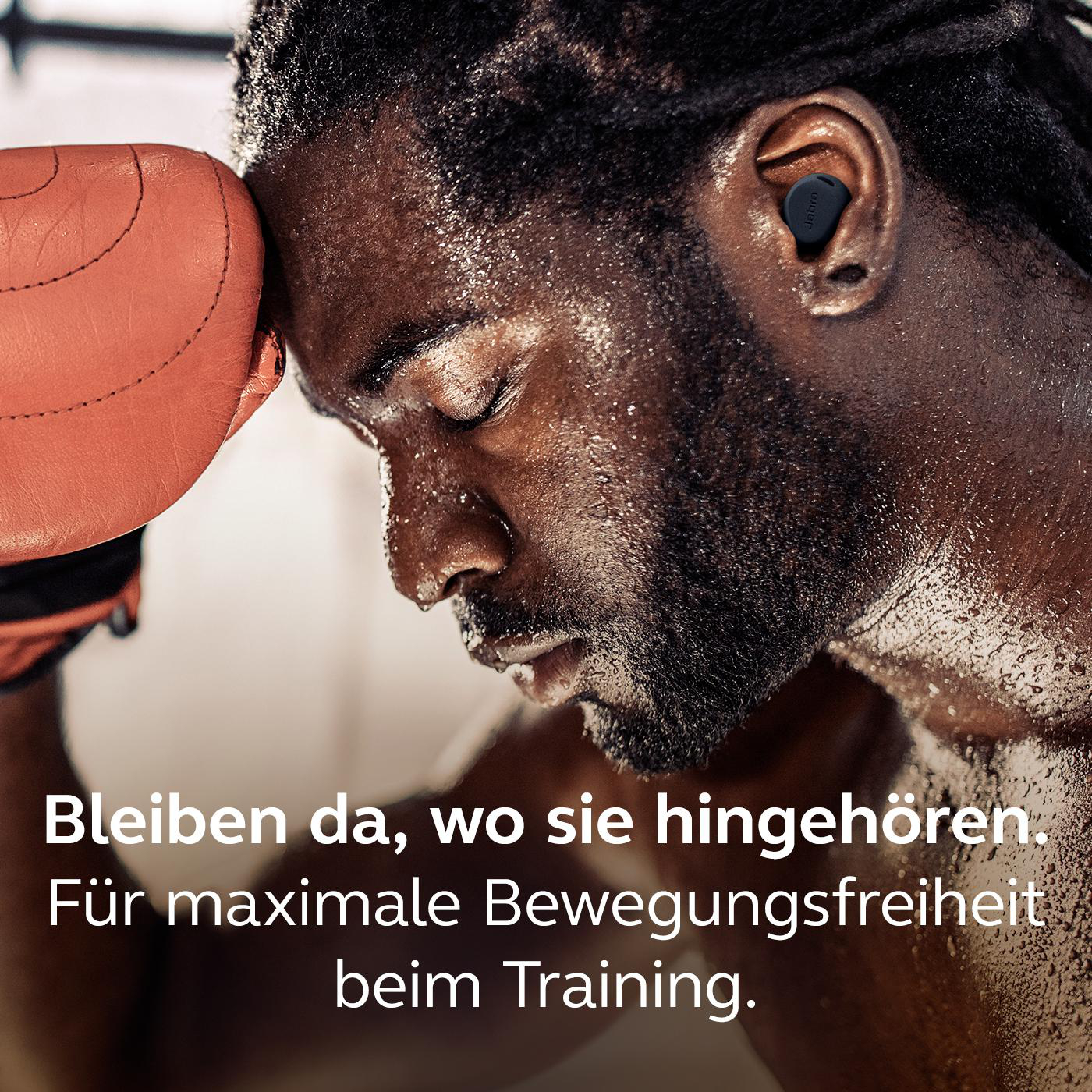 Schwarze Ohrhörer im Ohr eines Mannes, der sich an einen Boxhandschuh lehnt, mit deutschem Text.
