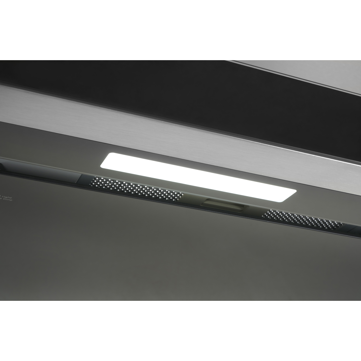 Close-up van de onderkant van een grijze afzuigkap met een helder wit licht en ventilatiegaten.