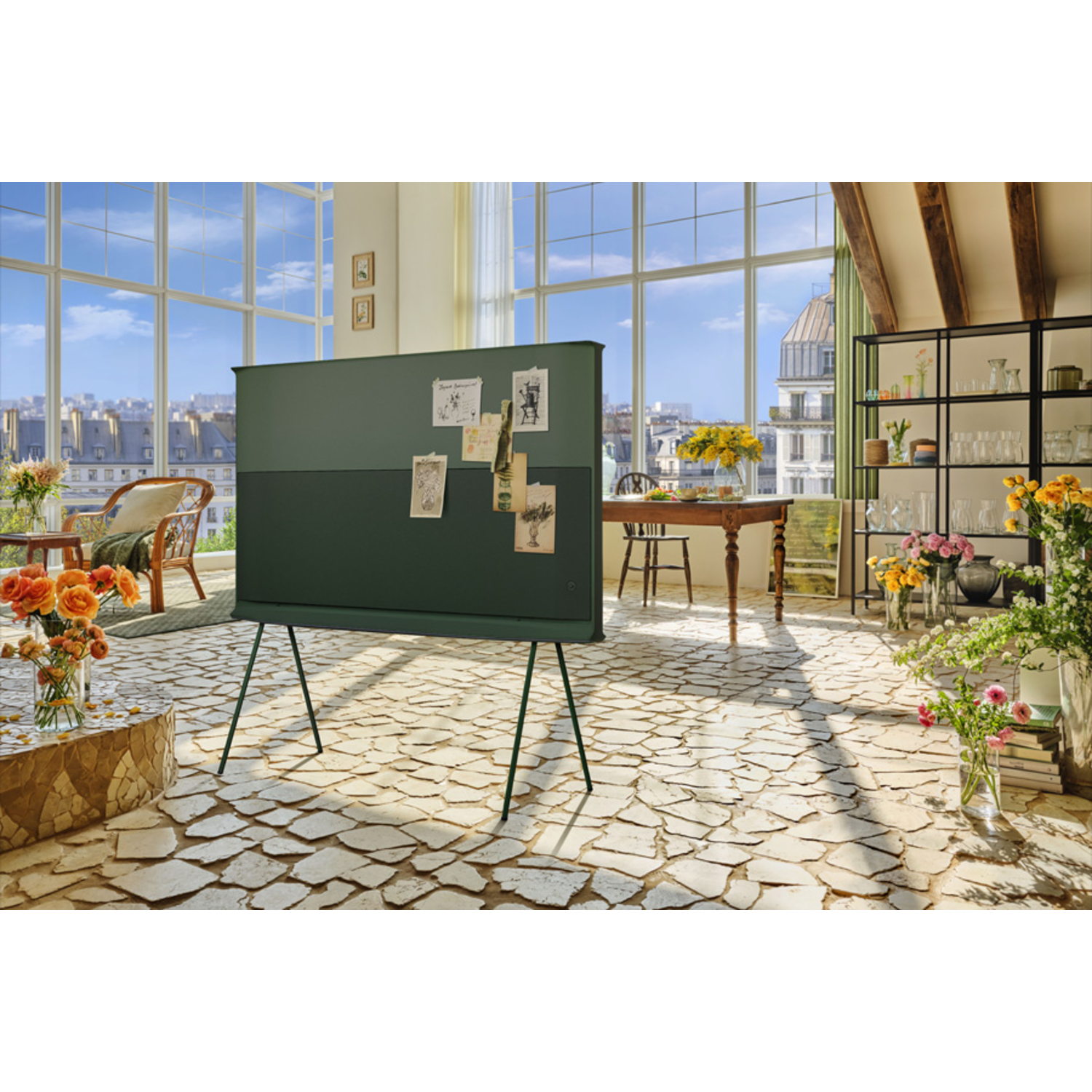 Living room with a large green art piece, windows, plants, and a city view.