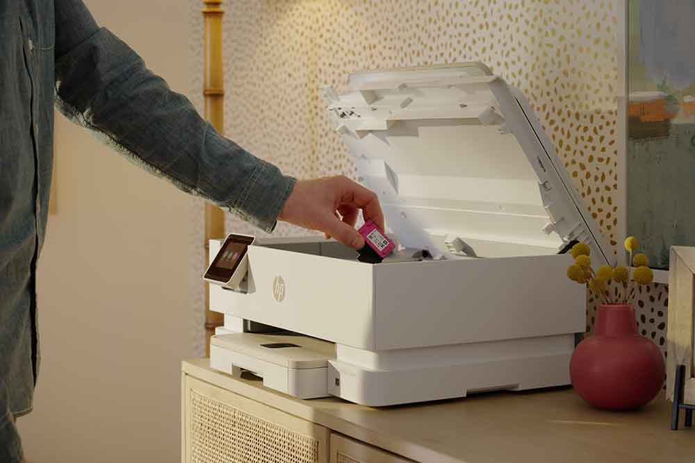 Man inserts a new ink cartridge into a printer.