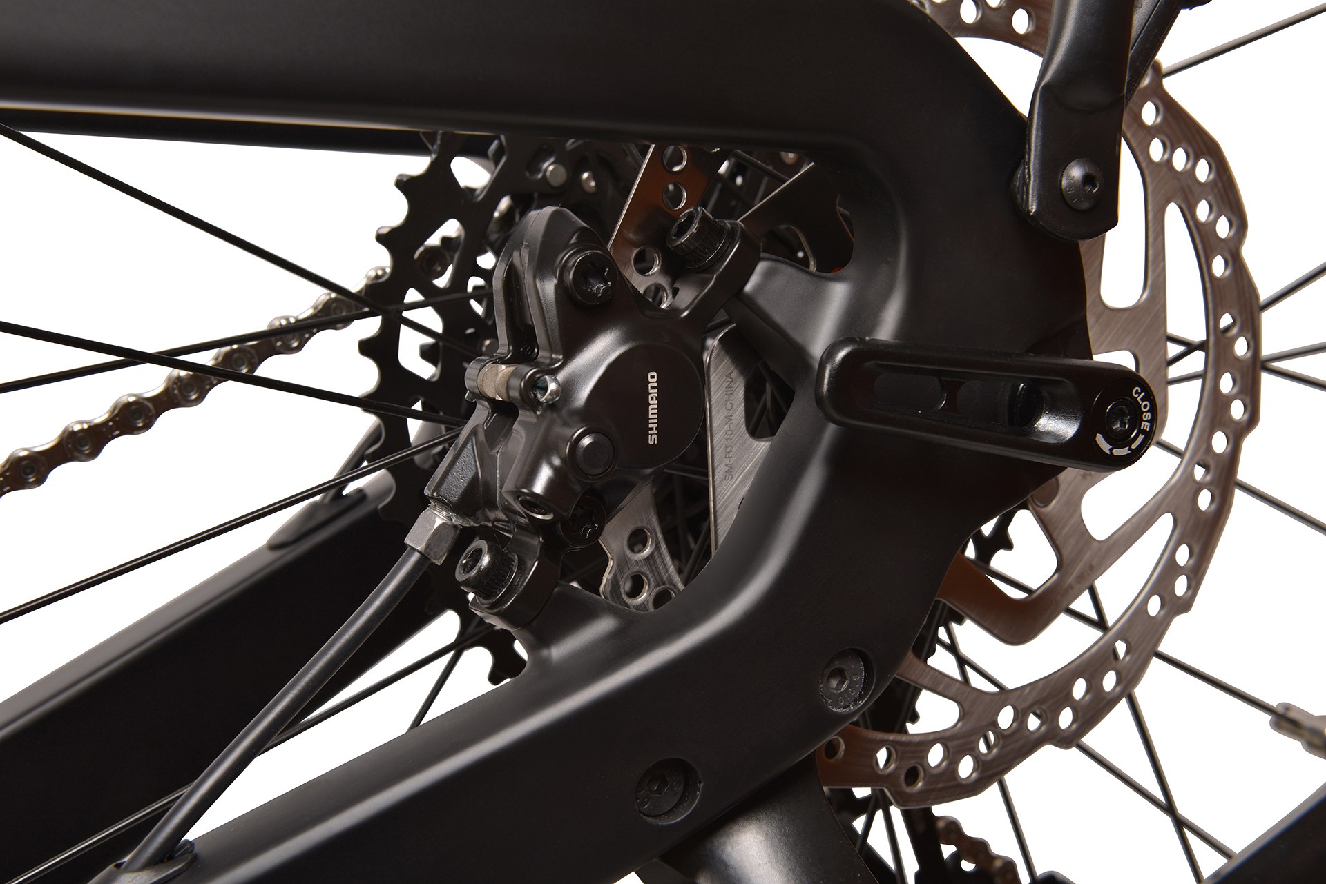 Zbliżenie tylnego koła roweru z systemem hamulcowym Shimano, łańcuchem i zębatką.